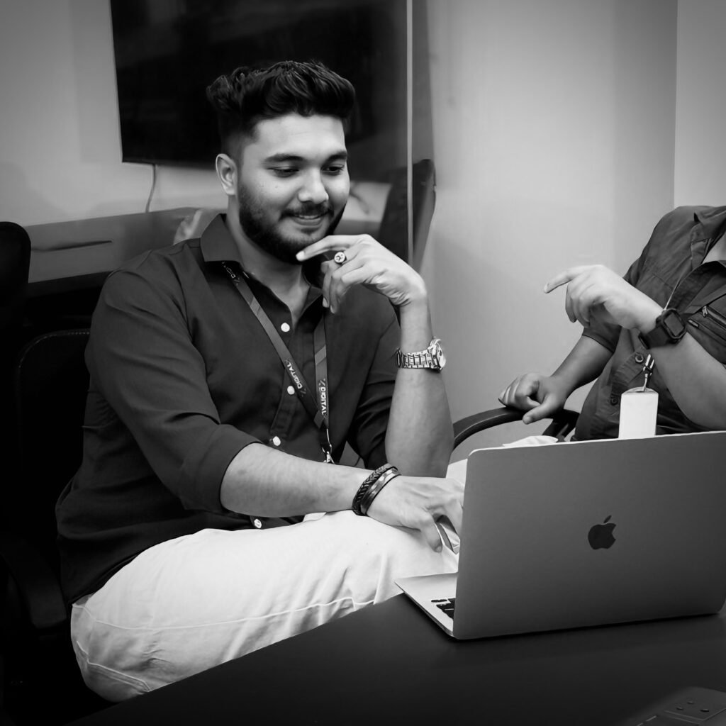 The best social media marketer in Palakkad reviewing a campaign on a laptop in a black and white professional setting"